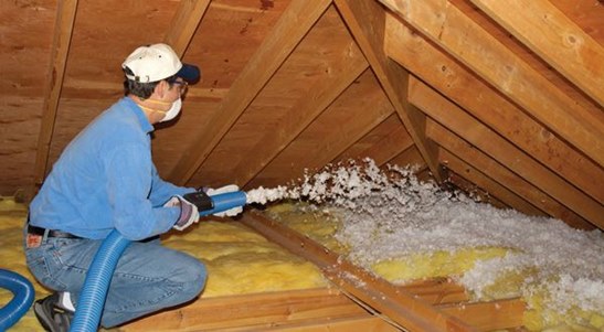 Technician installing blown-in attic insulation.