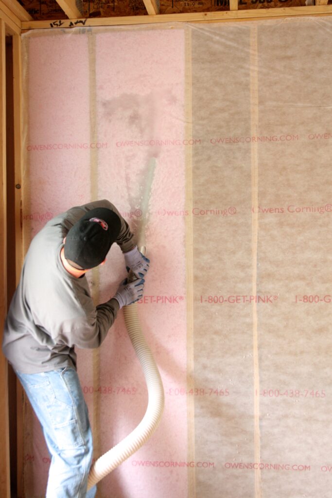 Technician installing blown insulation in a wall
